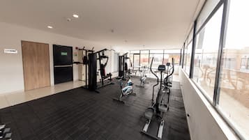 Un gimnasio con diferentes equipos de ejercicio, una puerta de madera y una ventana con vistas al exterior.