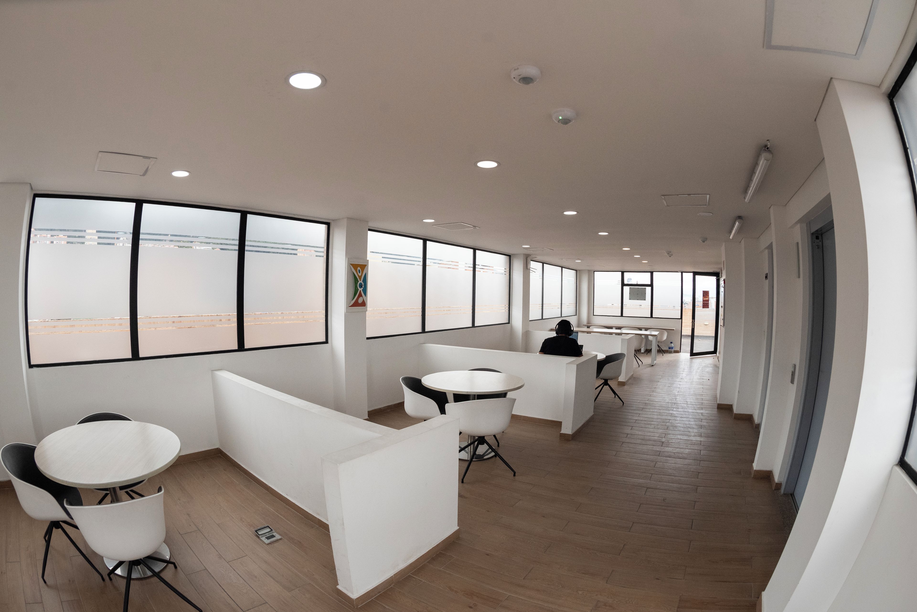 A modern office space with white partitions, round tables, and chairs.