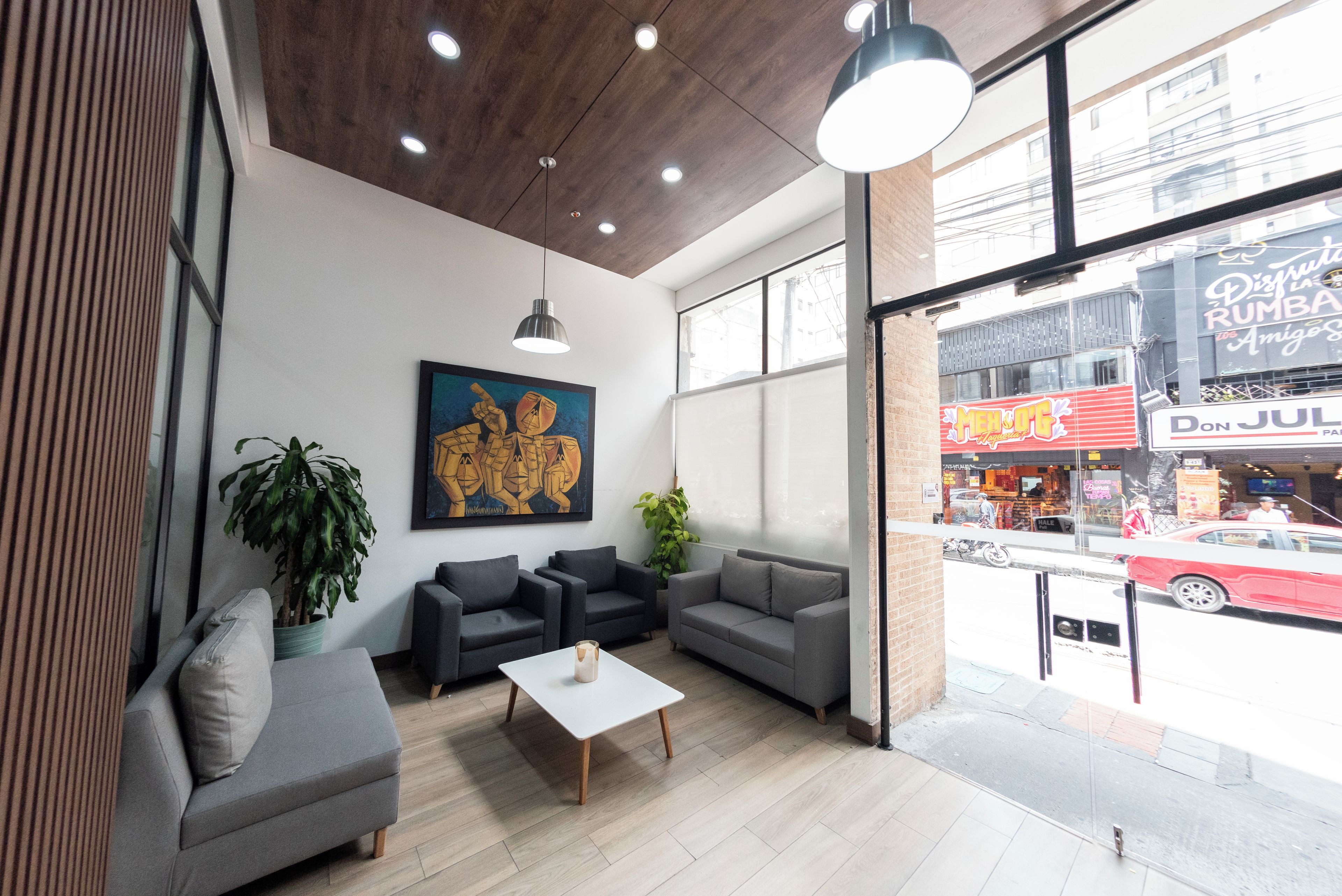 A modern interior with a seating area, a painting, and a view of the street outside.