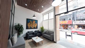 A modern interior with a seating area, a painting, and a view of the street outside.