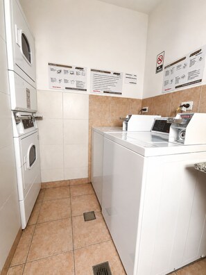 A laundry area with a washing machine, dryer, and stacked drying racks. - Frente a River. Balcón sobre Av. Libertador, con vista al Monumental. (Buenos Aires)