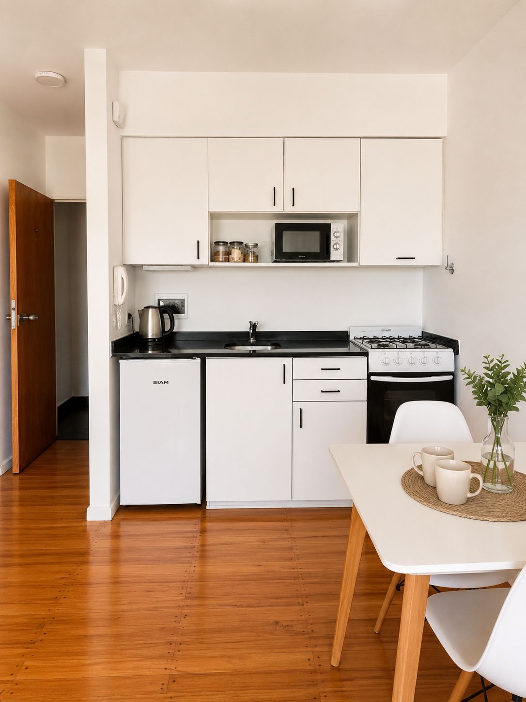A compact kitchen with white cabinets, a microwave, a gas stove, and a refrigerator.