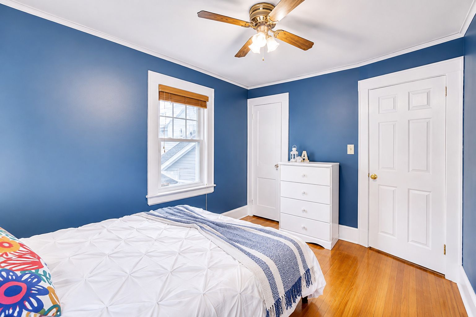 A bedroom with a bed, a dresser, a window, and a ceiling fan.
