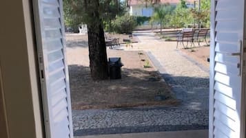 An open door leading to a patio area with a gravel path, a tree, and outdoor furniture.
