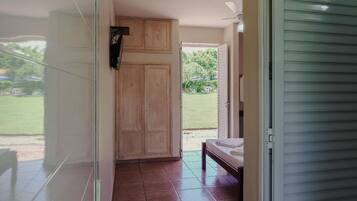 A room with a bed, a wardrobe, and a door leading to an outdoor area.