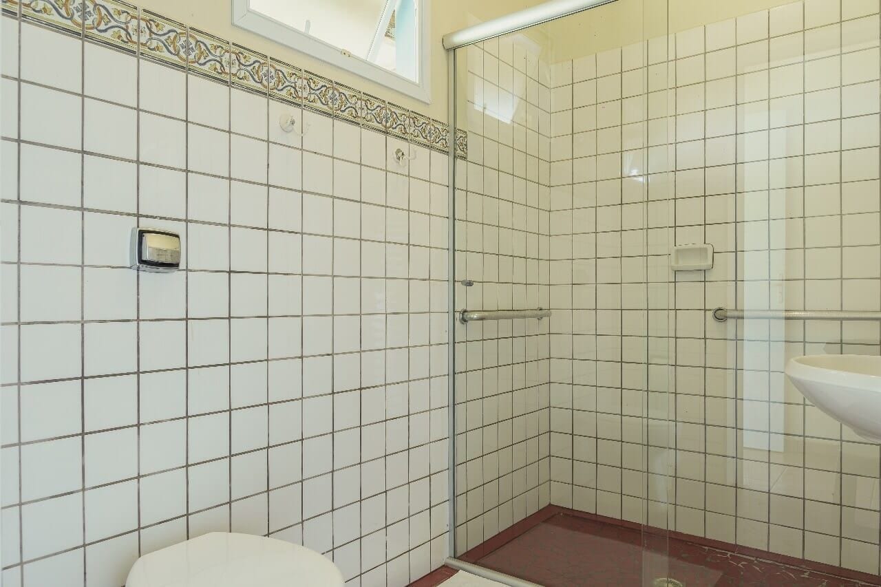 Un baño con ducha azulejada, inodoro y lavamanos.