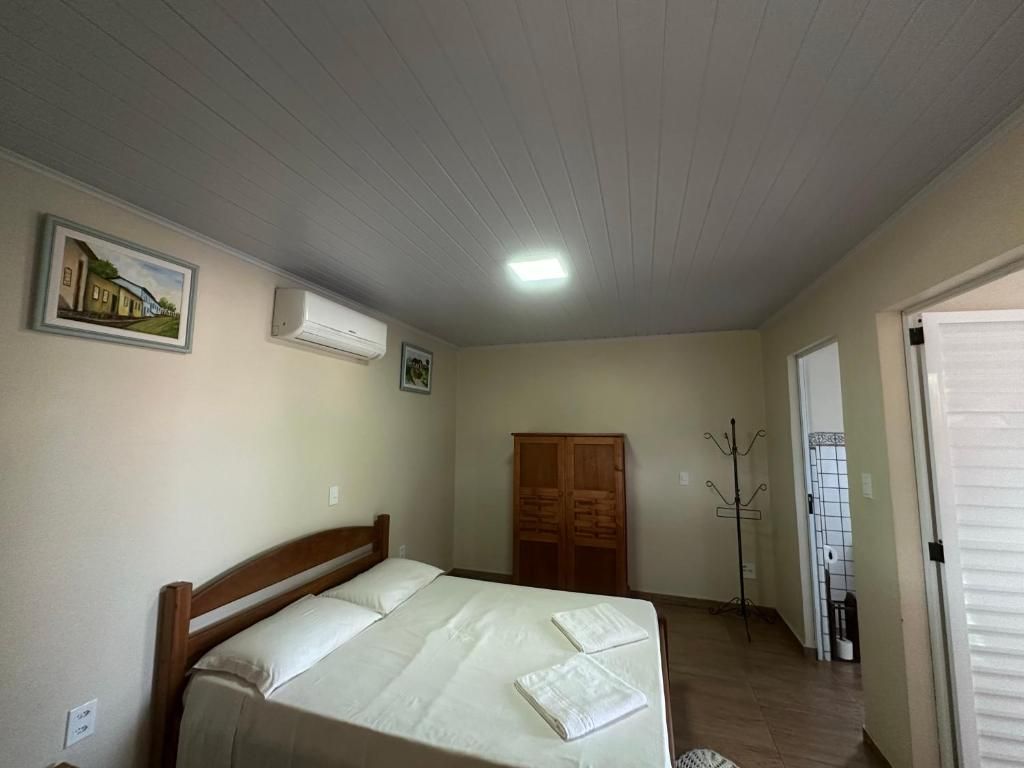 Un dormitorio con cama, armario, aire acondicionado y perchero.