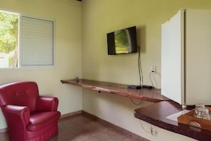 A room with a red leather chair, a flat-screen TV mounted on the wall, a white refrigerator, and a wooden counter.
