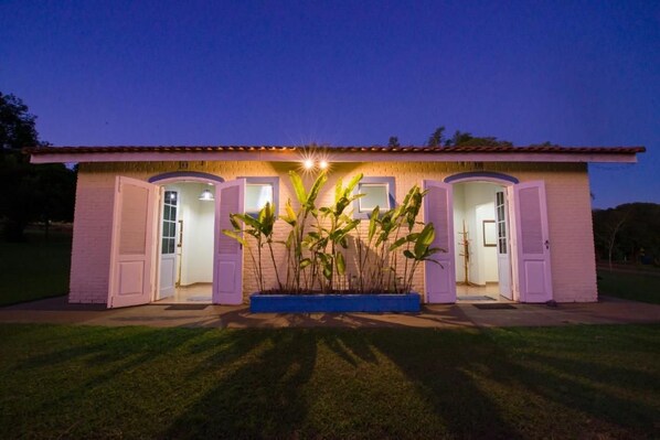 Una casa de dos pisos con techo plano, un porche delantero y una maceta grande con plantas.