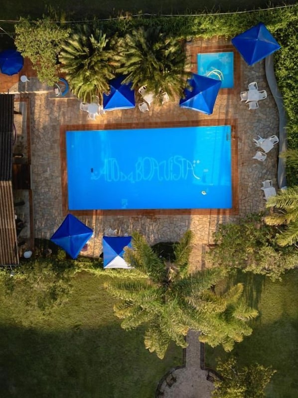 A swimming pool with a blue sign, surrounded by greenery and outdoor furniture.