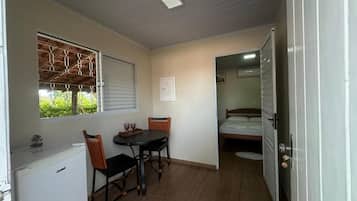 A compact room with a kitchenette, a dining area with a table and chairs, and a bed.