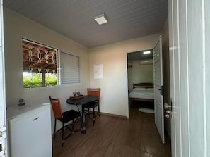 A compact room with a kitchenette, a dining area with a table and chairs, and a bed.