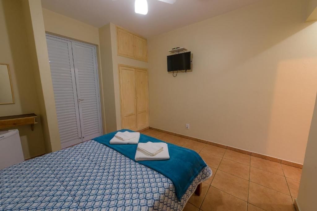 Ein Schlafzimmer mit einem Bett, einem an der Wand montierten Fernseher und einem Kleiderschrank.