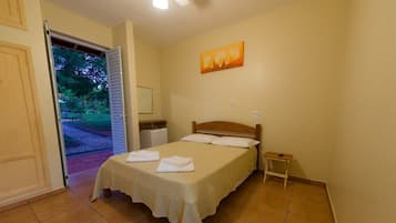A bedroom with a bed, a nightstand, a painting, and a door leading to an outdoor area.