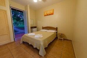 A bedroom with a bed, a nightstand, a painting, and a door leading to an outdoor area.