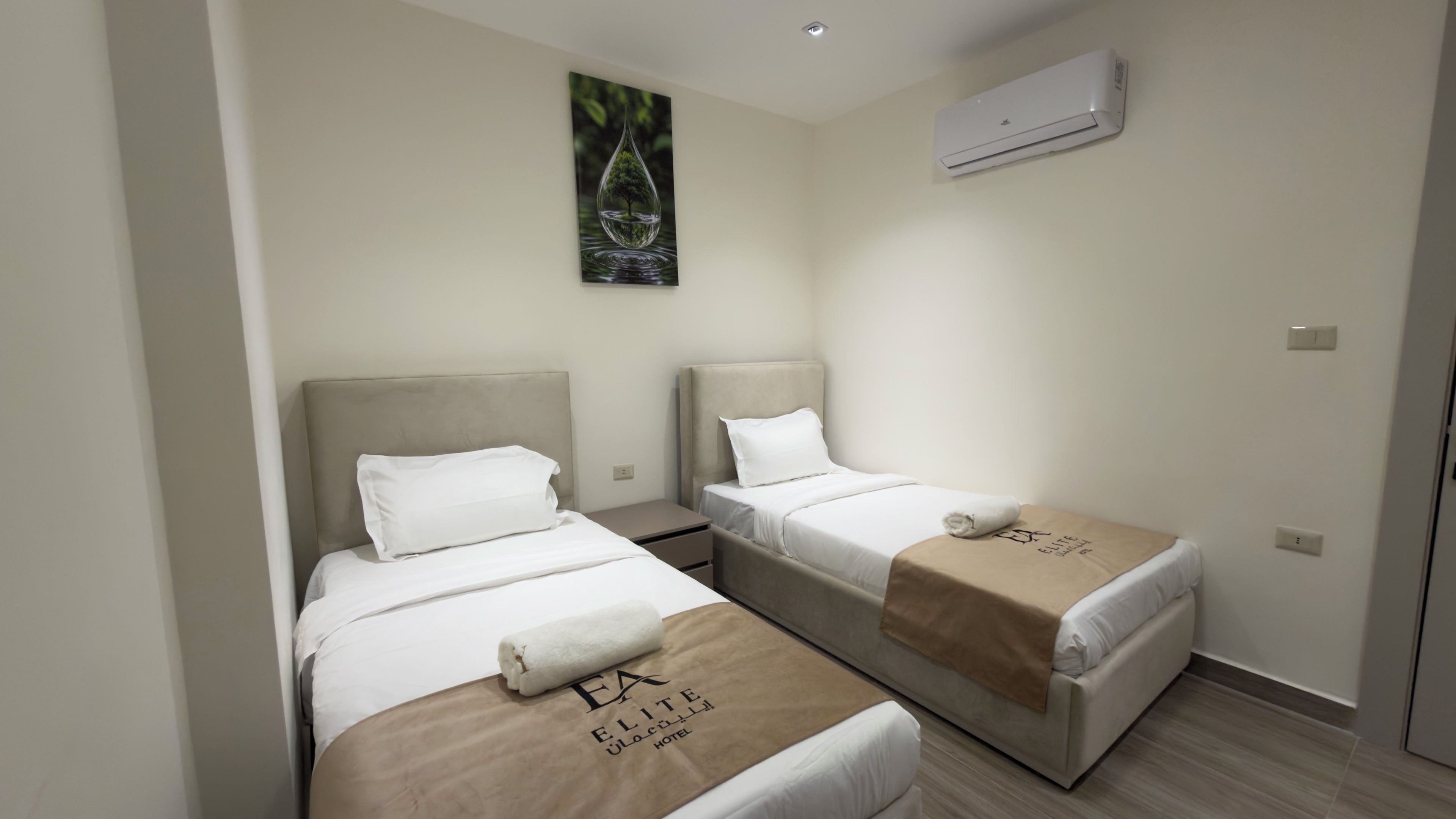 Ein Hotelzimmer mit zwei Betten, einem Bild an der Wand und einer Klimaanlage.