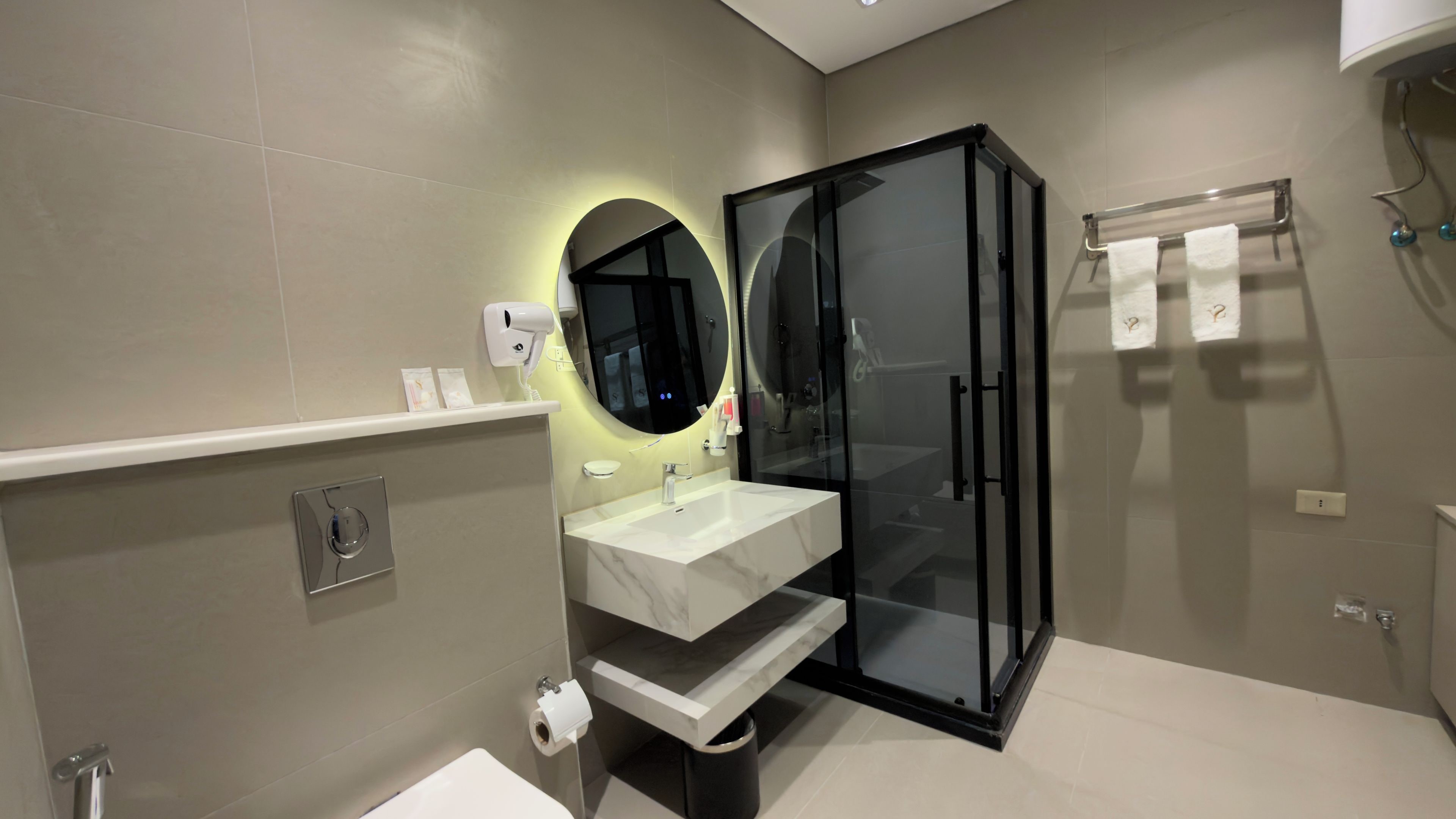 Un bagno moderno con doccia vetrata, lavabo in marmo e specchio a parete.