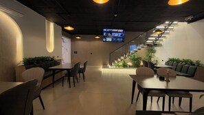 A modern interior with a staircase, seating areas, and a projection screen displaying content.