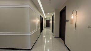 Ein Hotelkorridor mit poliertem Boden, Wandleuchten und Türen zu Zimmern.