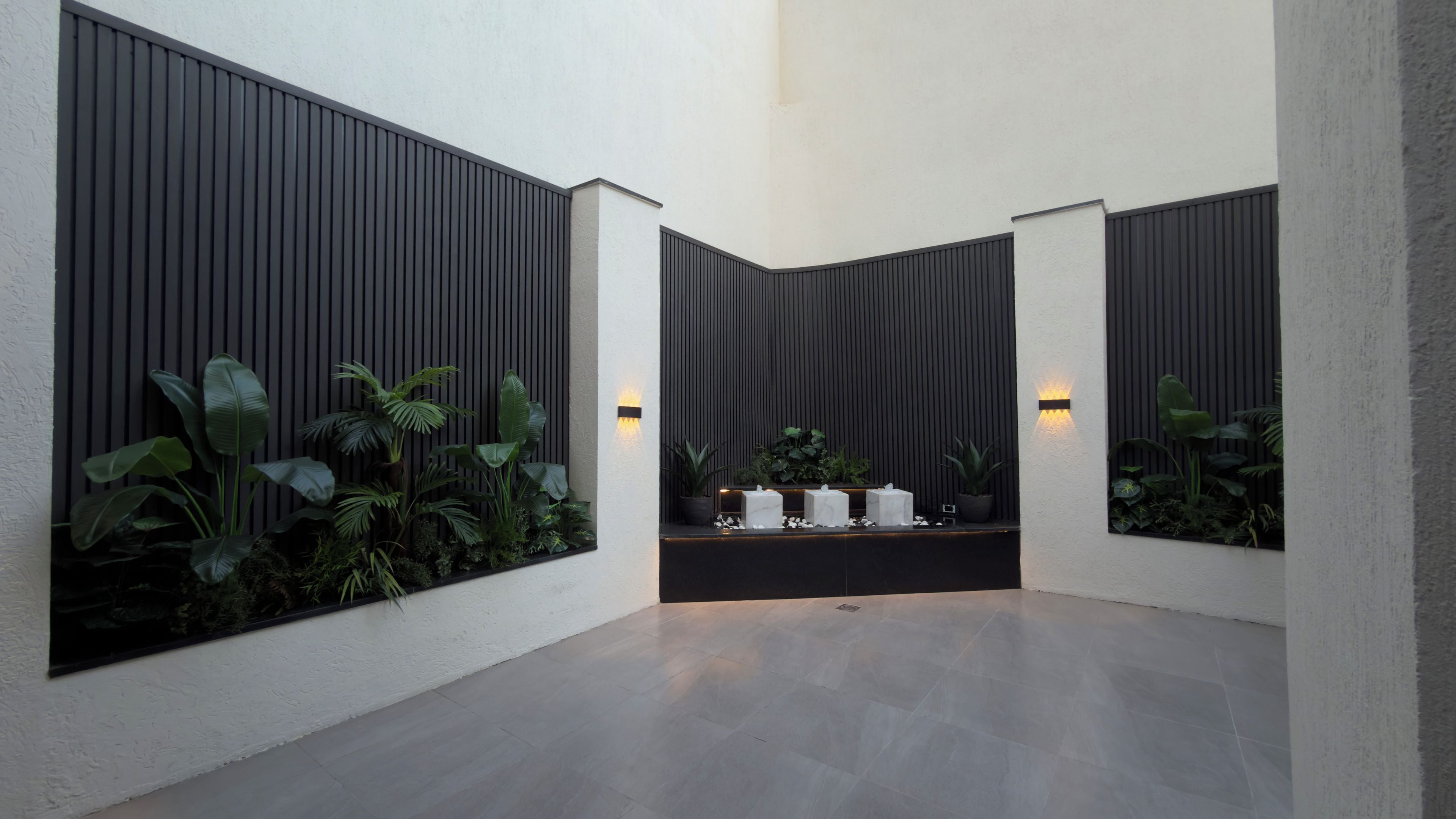 Un intérieur moderne au design minimaliste, comprenant un comptoir d’accueil, des plantes en pot et un luminaire.