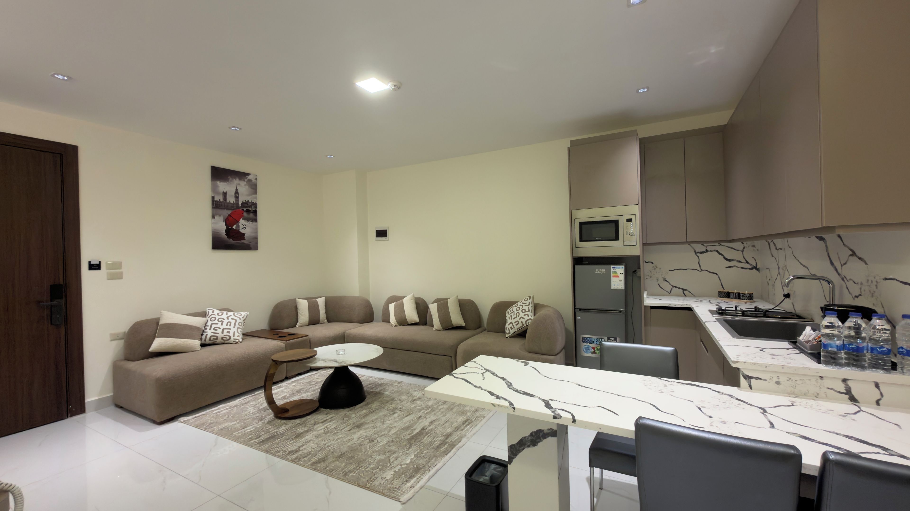 En moderne stue med en hjørnesofa, et sofabord og et spiseområde med et bord med marmorplade.