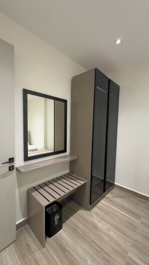 A modern bathroom with a mirror, a bench, and a trash bin.