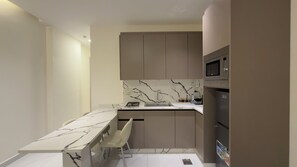 A compact kitchen with a marble countertop, a built-in microwave, and a gas stove.