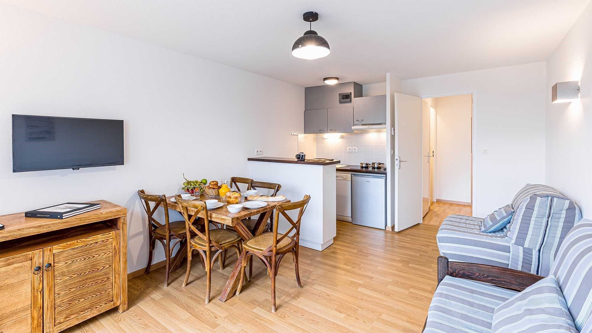 Un espacio habitable compacto con comedor, kitchenette y sofá.
