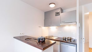 Cocina compacta con encimera de madera, una cámara, lavavajillas y armarios grises.