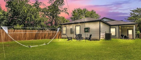 A single-story house with a fenced backyard, a trampoline, and a patio area with outdoor furniture.