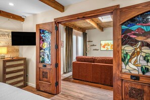 A room with a wooden door, a sofa, a television, and a wall-mounted shelf. - Designer Santa Fe Condo, Communal Pool and Hot Tub (Santa Fe)