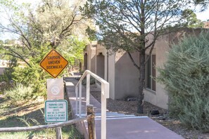 A caution sign for uneven sidewalks, a no-smoking sign, and a warning about slippery conditions on parking lots, pathways, and steps. - Designer Santa Fe Condo, Communal Pool and Hot Tub (Santa Fe)