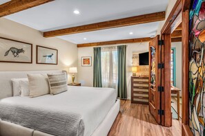 A bedroom with a bed, a nightstand, a lamp, a dresser, and a TV. - Designer Santa Fe Condo, Communal Pool and Hot Tub (Santa Fe)