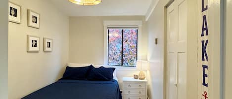 A bedroom with a bed, bedside table, lamp, and a bench.