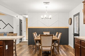 Eine moderne Küche mit Essbereich, Holzschränken und einer Chandelier.