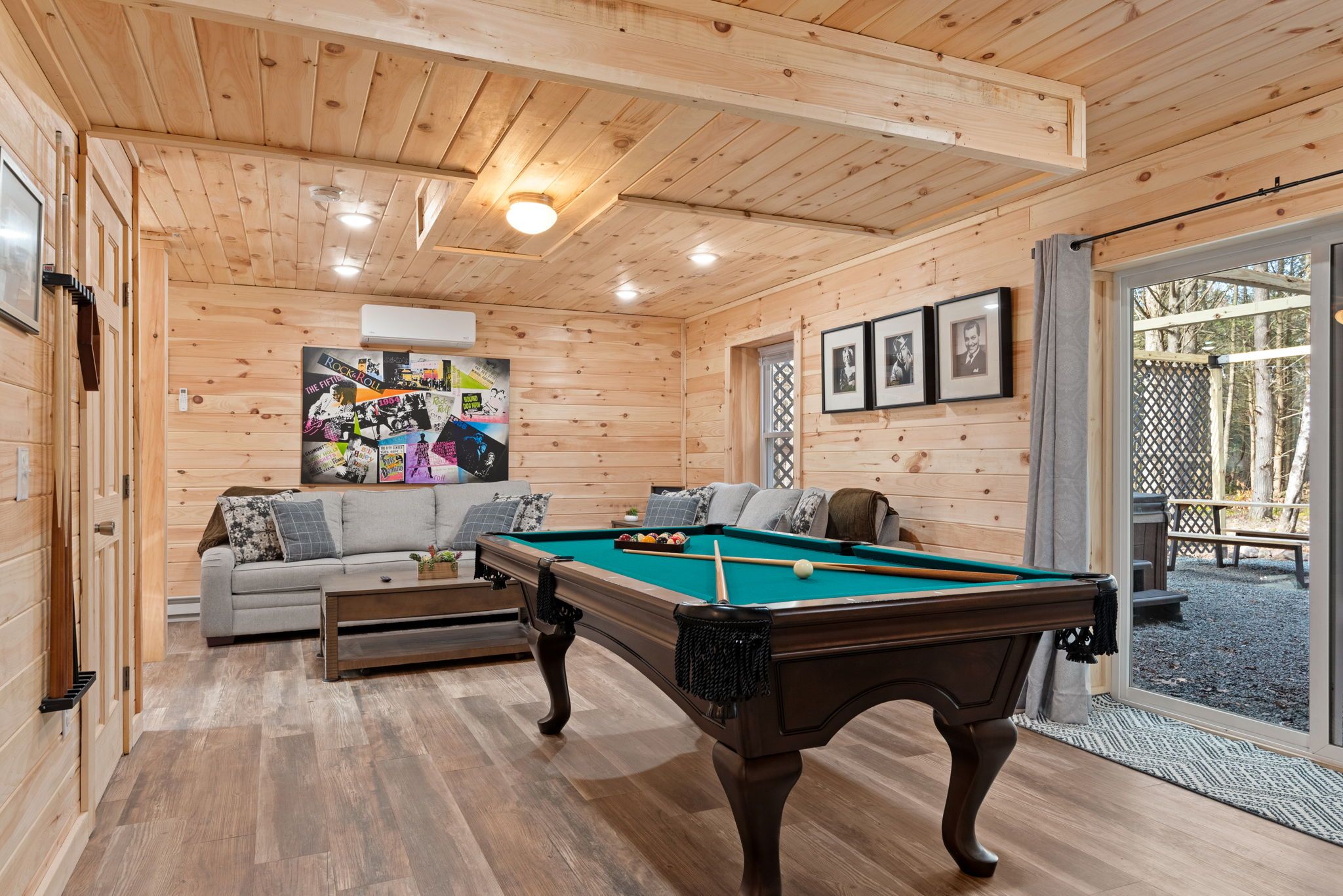 Een houten interieur met een pooltafel, een bank en een ingelijste poster aan de muur.