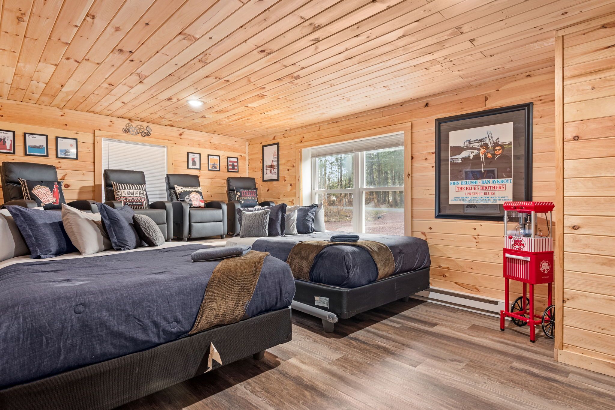 A cozy room with a large bed, two smaller beds, a red cart, and wooden walls.