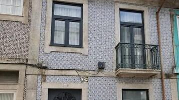 Un edificio con fachada de tejas, una puerta oscura y un balcón.