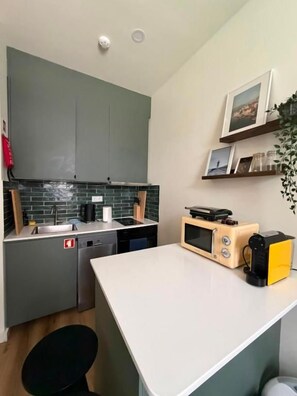 Cocina compacta con lavavajillas, microondas y una pequeña isla. Cuenta con dos armarios y un lavabo.