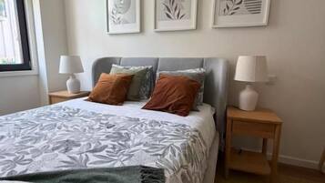 Un dormitorio con una cama, dos mesitas de noche y tres cuadros en la pared.