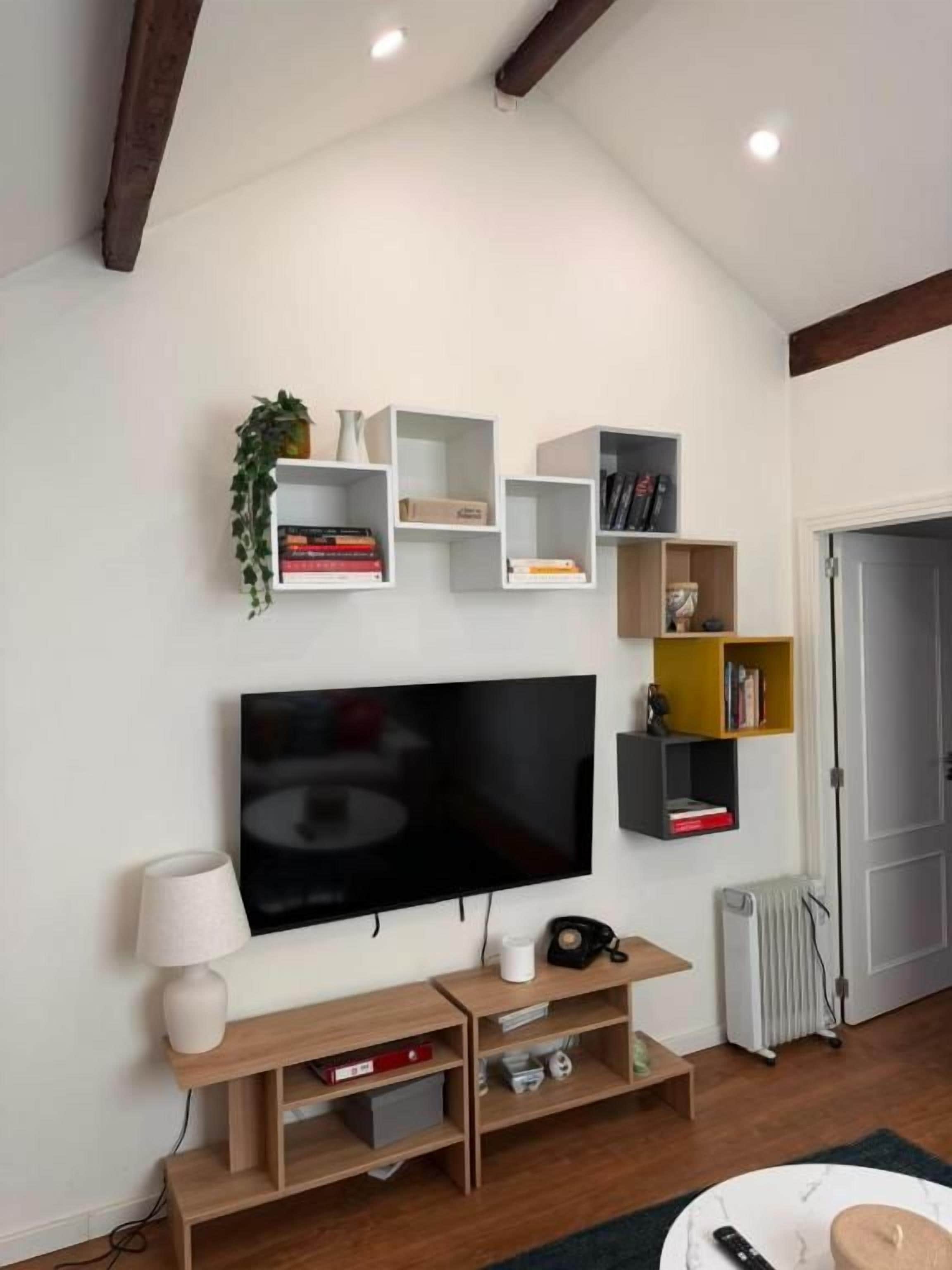 A living room with a flat-screen TV, wooden shelves, and a radiator.