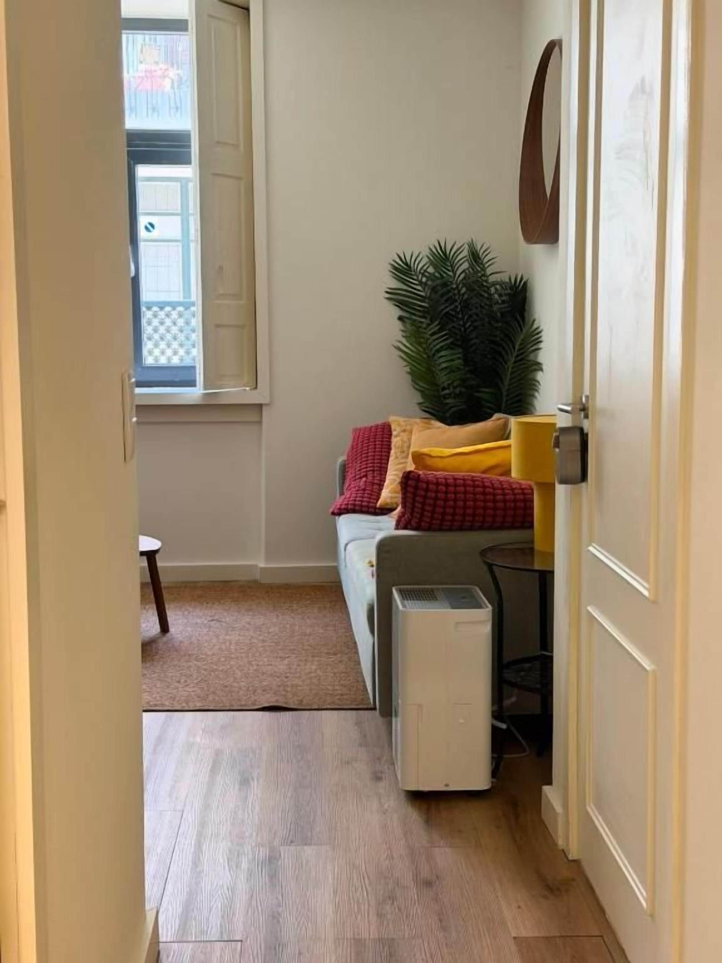 A narrow hallway with a bed, a small table, and a heater.