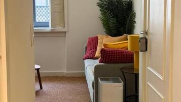 A narrow hallway with a bed, a small table, and a heater.