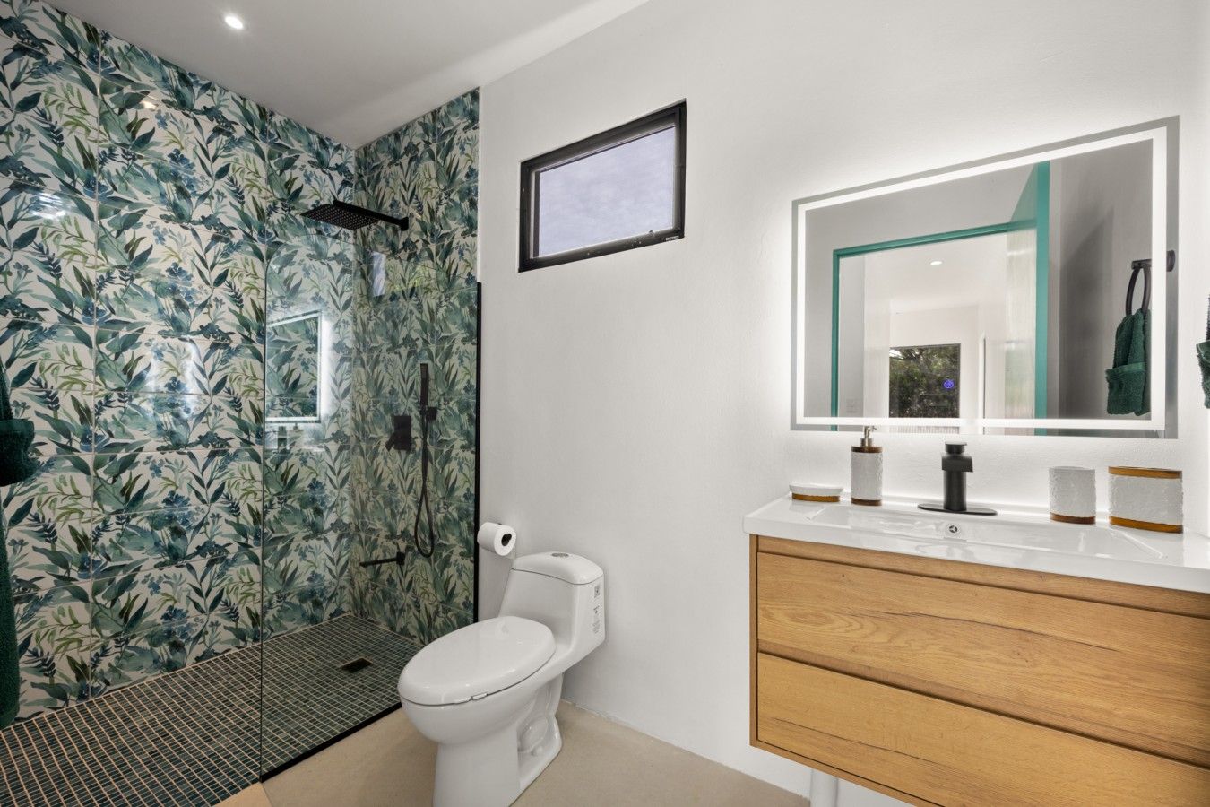Une salle de bain équipée d’une douche, de toilettes et d’un meuble-lavabo avec un miroir.