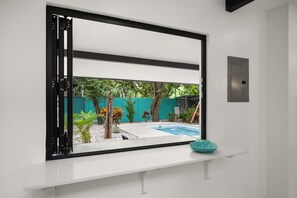 Ein Zimmer mit Fensterblick auf einen Swimmingpool und einen Garten.