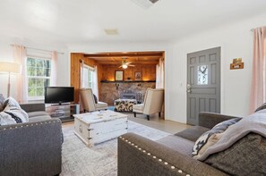 Una sala de estar con televisión, sofás, una mesa de centro y una chimenea.