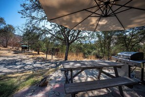 An outdoor picnic area with a table and benches, a grill, and a covered seating area. - Agate Ranch - Views | River Access | EV Charging (Three Rivers)