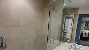 Une salle de bain moderne dotée d’une douche à parois de verre, d’une baignoire et d’un meuble-lavabo avec deux vasques.