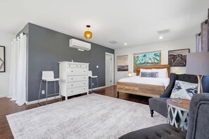 Ein Schlafzimmer mit Bett, Schminktisch, Stuhl und Bildern an der Wand.