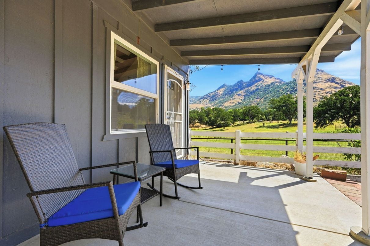 Eine überdachte Veranda mit Korbstühlen und Blick auf die Berge.